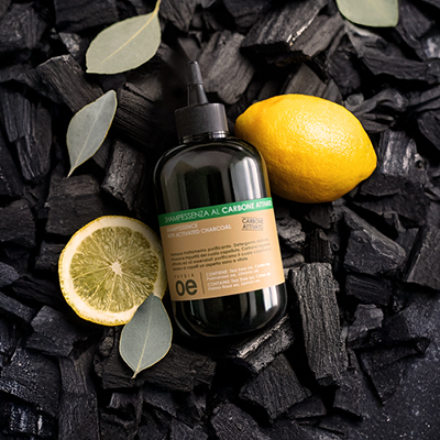 immagine del prodotto dello shampoo al carbone attivato ambientato su sfondo nero con carbone e limoni 